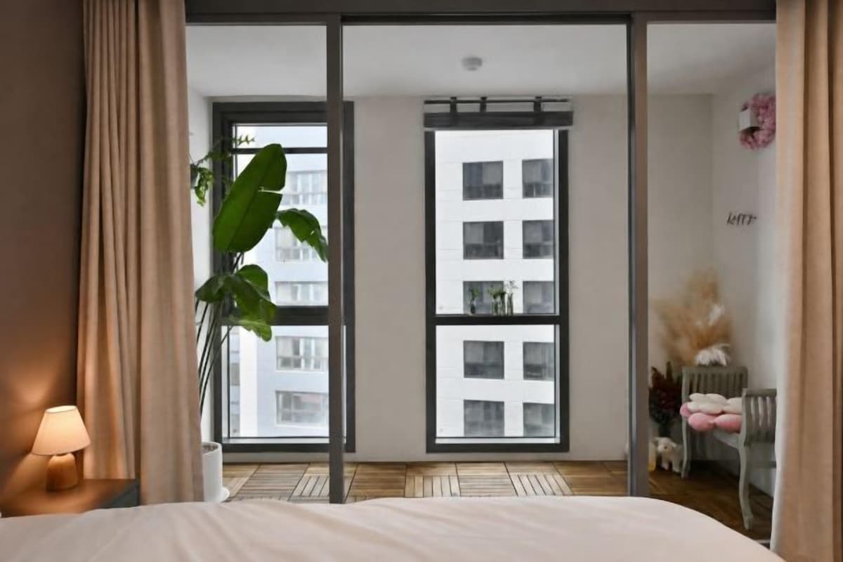 Una habitación de hotel con cama, ventana grande y vista a la ciudad.