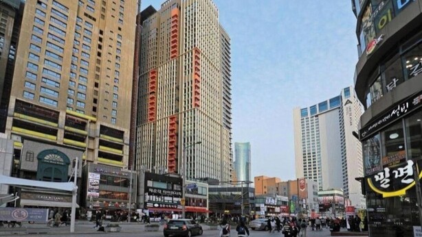 A busy urban street with tall buildings, including a prominent high-rise with a unique facade. - Haeundae Lamer Stay (Busan)