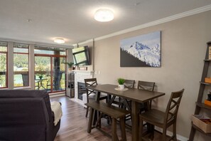 A dining area with a wooden table and chairs, a fireplace, and a TV mounted on the wall.