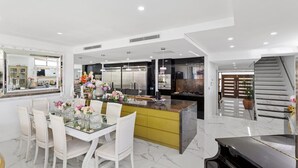 Una cocina moderna con una isla central, mesa de comedor blanca con sillas y un piano.
