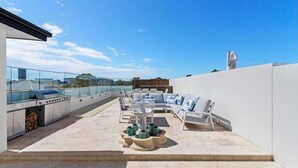 Un patio en la azotea con mobiliario exterior, una parrilla y vistas del horizonte de la ciudad.