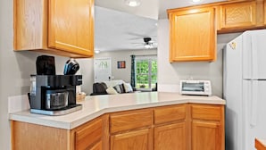 A modern kitchen with wooden cabinets, a coffee maker, a toaster, and a refrigerator.