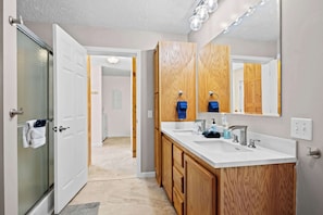 Un baño moderno con tocador de doble lavabo, armarios de madera y un espejo grande.