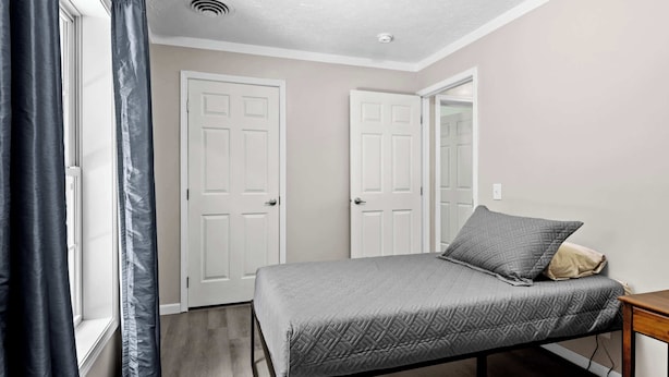 A bedroom with a bed, a window with curtains, and two white doors.