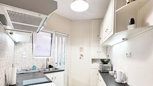 A modern kitchen with white cabinets, a black countertop, and a ceiling light.