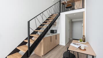 A modern kitchen with a wooden staircase and a dining area.