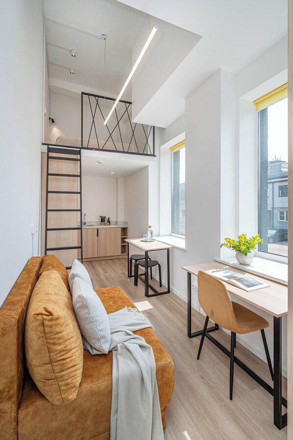 A modern apartment with a loft bedroom, a kitchen, and a dining area. - Weloft (Vilnius)