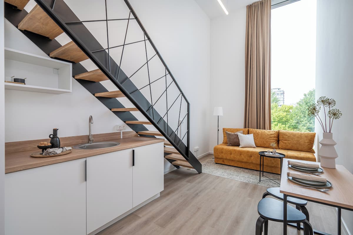 A modern kitchen with a wooden countertop, a built-in sink, and a black staircase with wooden steps.