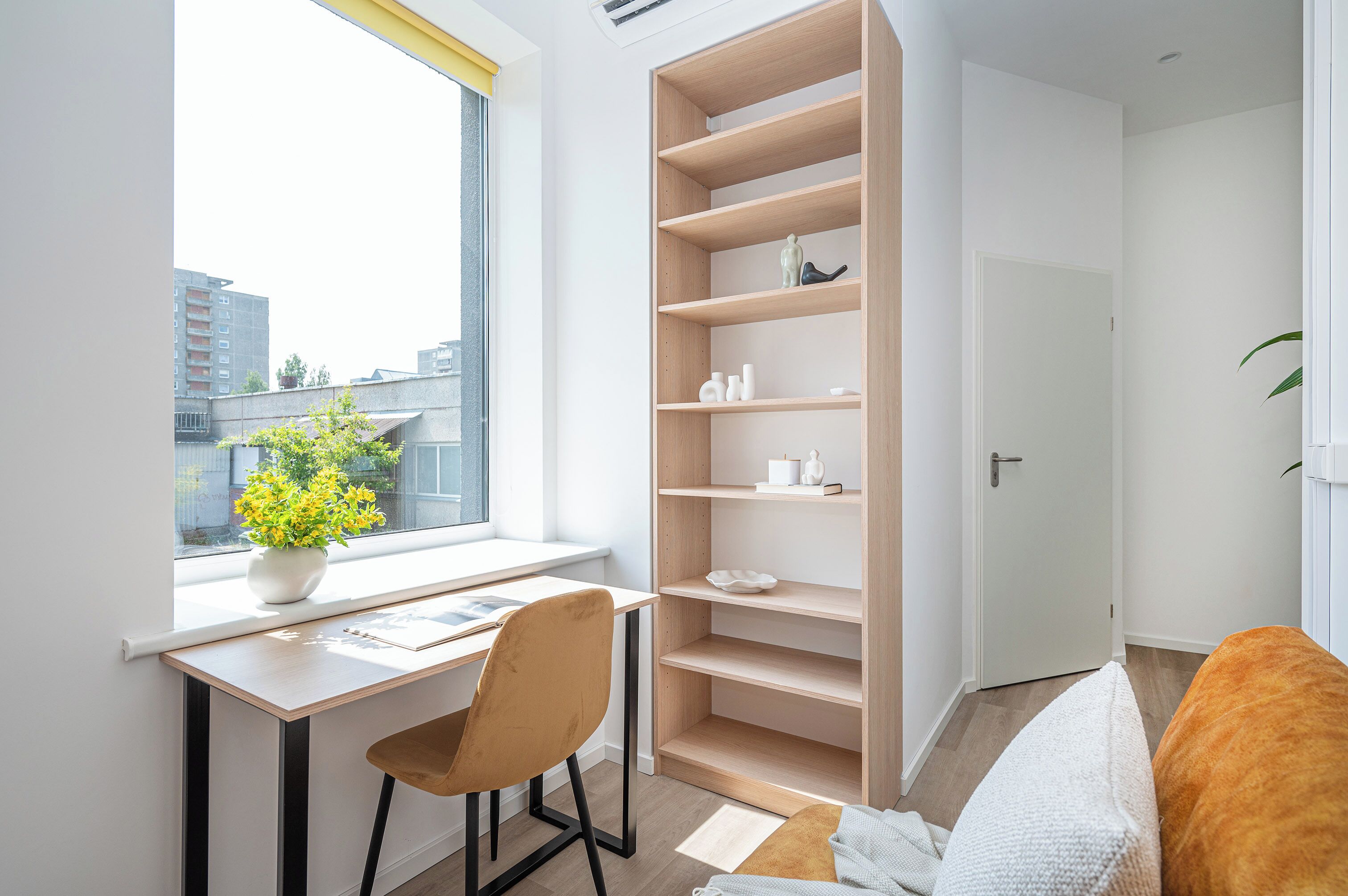 Una habitación pequeña con escritorio, silla y estantería empotrada.