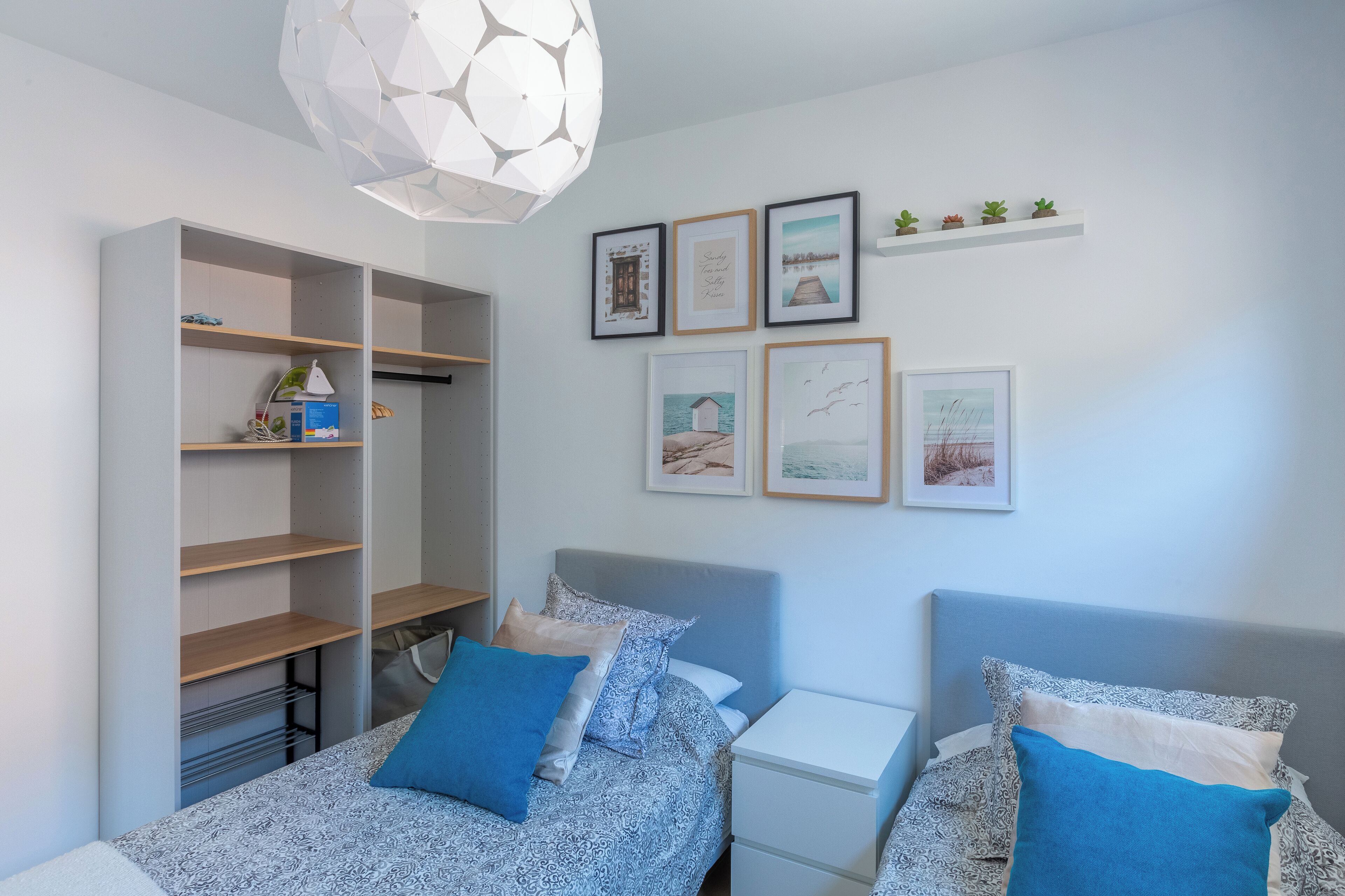 Een slaapkamer met een bed, nachtkastjes, een kledingkast en wanddecoratie.