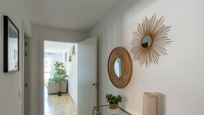 A hallway with a glass console table, a potted plant, a mirror, and a sunburst wall decoration. - Apartment Catania in Aguadulce - Almeria. Equipped, elegant, and with sea views (Aguadulce)