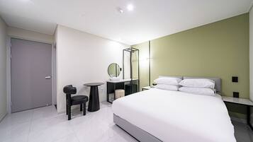 Una habitación de hotel moderna con una cama grande, un escritorio, una silla, un espejo y un armario.