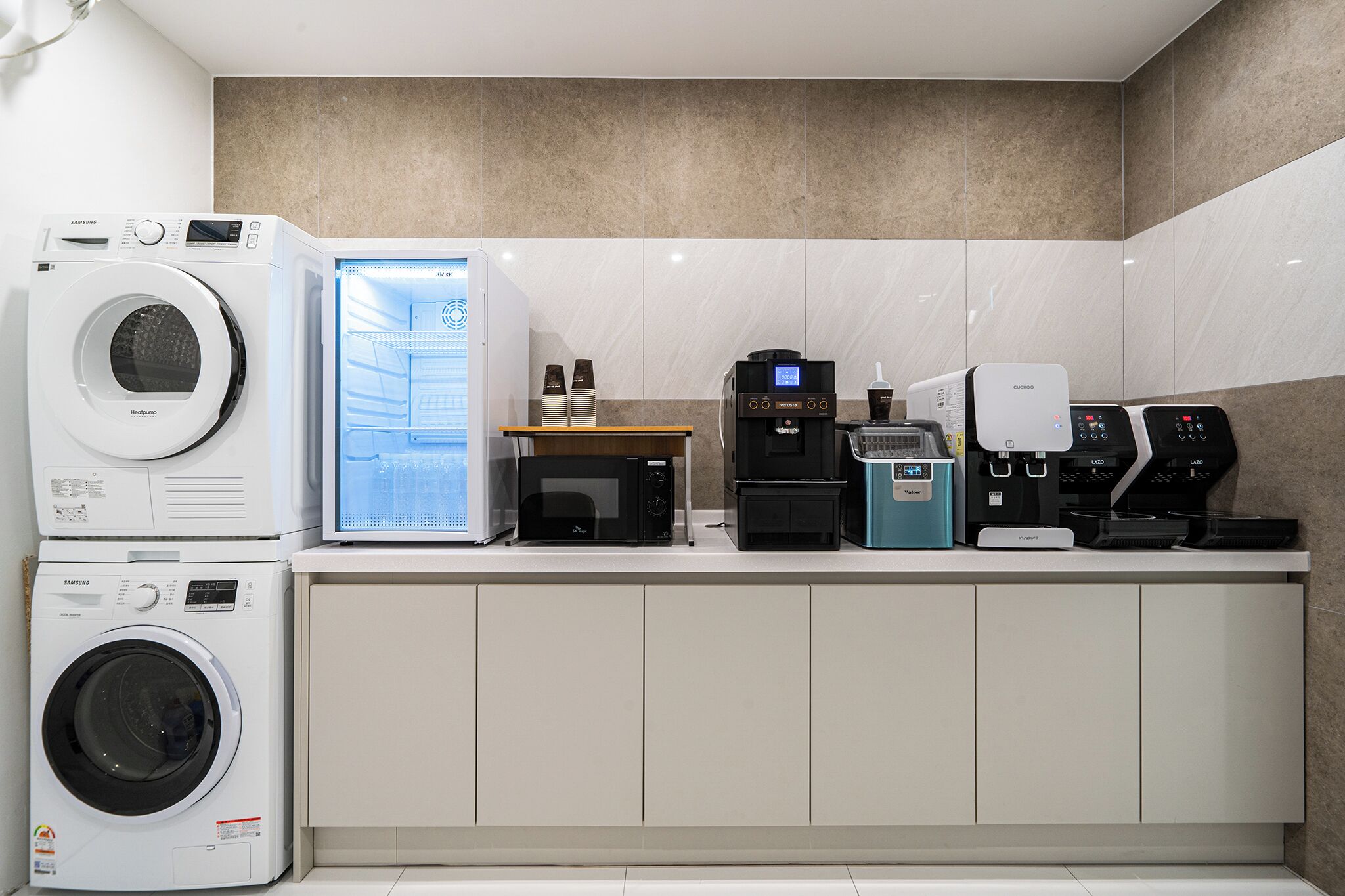 A modern kitchen with a built-in washer, microwave, coffee machine, and toaster.
