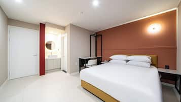 Una habitación de hotel moderna con una cama grande, un escritorio y un baño con espejo y lavamanos.