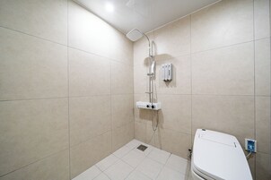 Un baño pequeño y moderno con ducha, inodoro y un panel de control en la pared.