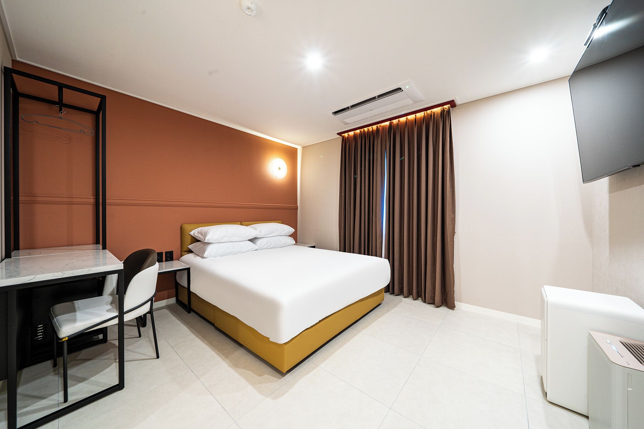 Une chambre d’hôtel équipée d’un lit, d’un bureau, d’une chaise, d’une télévision et d’un appareil de climatisation.