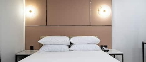 Een moderne hotelkamer met een groot bed, twee nachtkastjes, een telefoon en wandlampen.