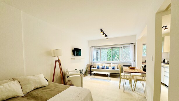 A bedroom with a bed, bedside table, lamp, and a view of the dining area. - Spectacular for 2 people in Mar del Plata, steps away from the beach. (Mar del Plata)