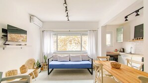 A modern bedroom with a bed, a dining table, chairs, a window with curtains, a TV, and a kitchen area. - Spectacular for 2 people in Mar del Plata, steps away from the beach. (Mar del Plata)