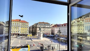 Een uitzicht op een stadsplein met gebouwen, een standbeeld en een tram.