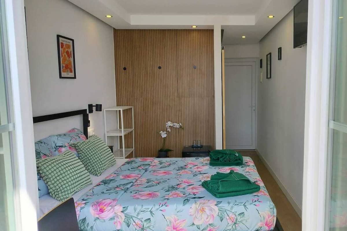 Une chambre à coucher avec un lit, une table de chevet, une étagère et une porte.