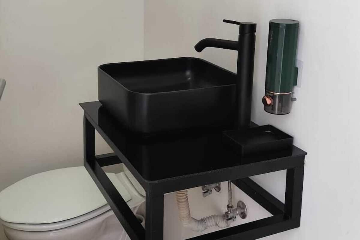 Une salle de bain avec un lavabo noir, des toilettes et un miroir.