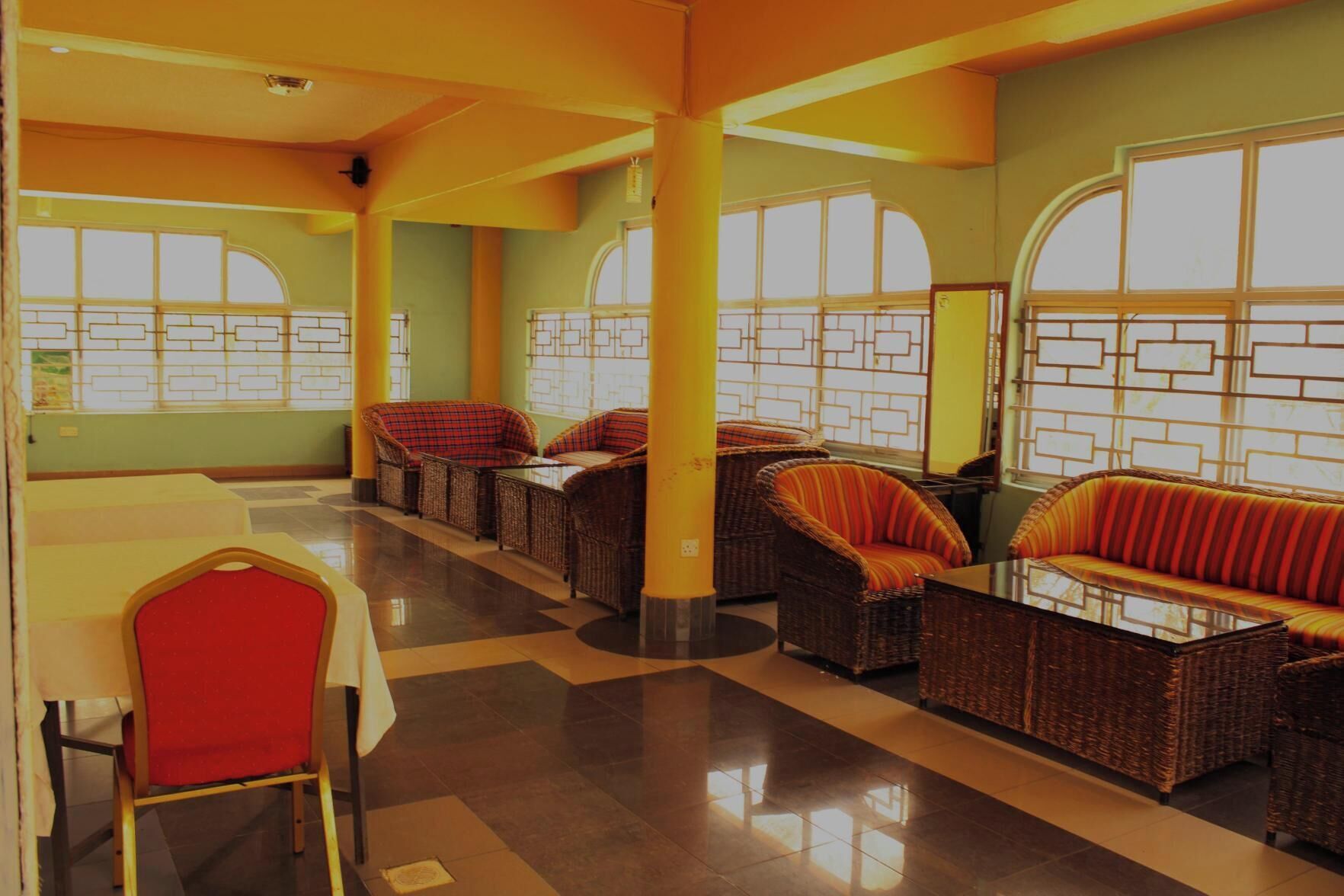 A spacious lobby with wicker sofas and chairs, large windows, and a tiled floor.