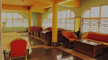 A spacious lobby with wicker sofas and chairs, large windows, and a tiled floor.