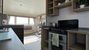 Een moderne keuken met een inbouwoven, een magnetron en houten planken boven het aanrecht.
