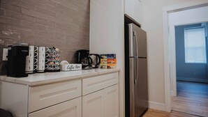 Cozinha com cafeteira, canecas, placa de café e geladeira.