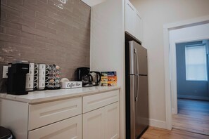 Una cocina con cafetera, tazas, letrero de barra de café y refrigerador.