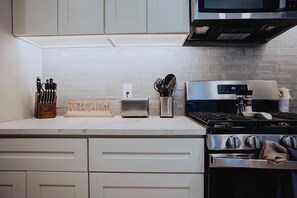 Una cocina con armarios blancos, un tostador, una estufa y un microondas.