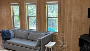 En hyggelig stue med en grå sofa, en hvid, lodden måtte og en lille, hvid skammel.
