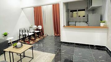 Een moderne woonkamer met een eetgedeelte, zwarte marmeren vloeren en een keuken die door een open deur zichtbaar is.
