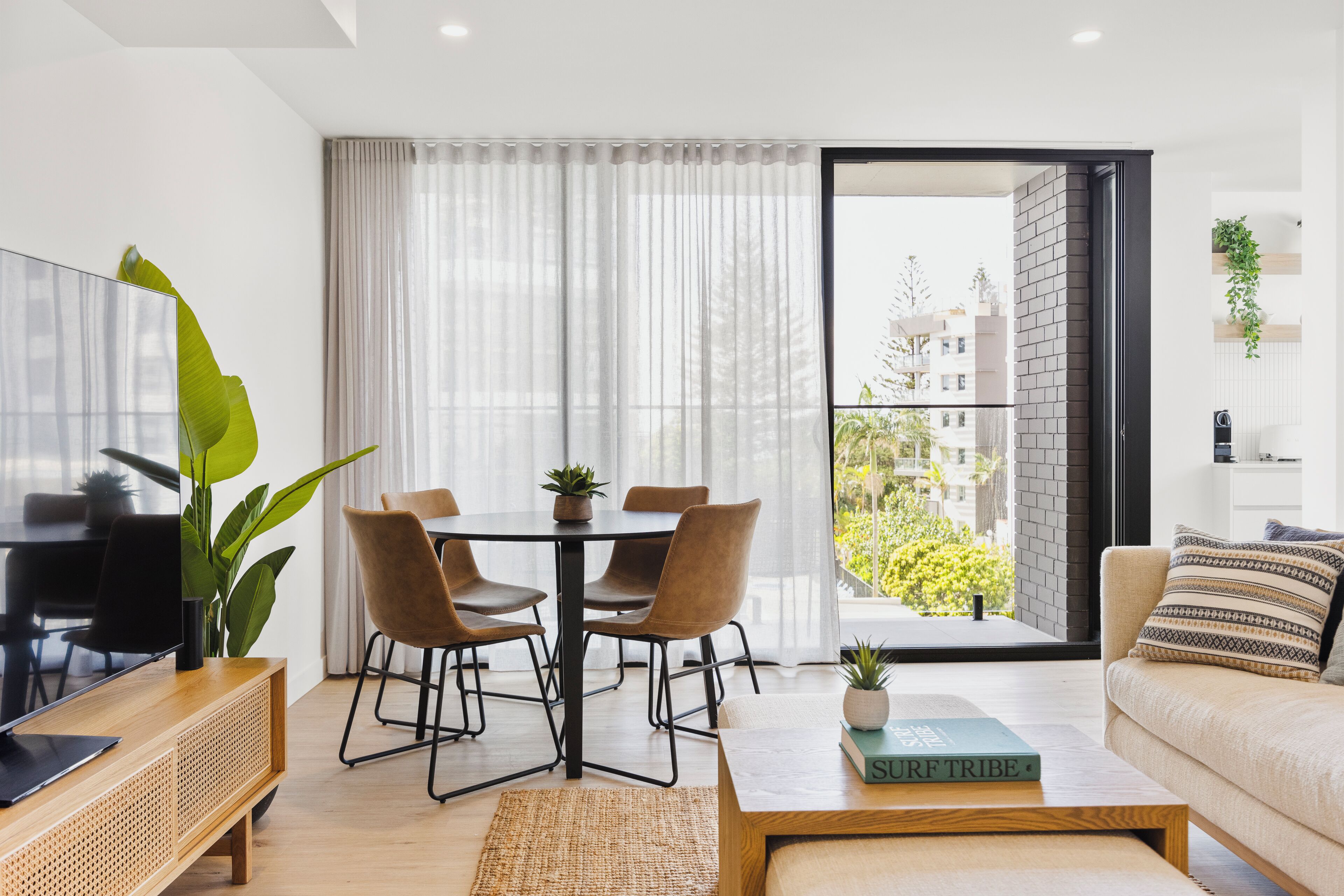 A modern living room with a dining area, a sofa, a coffee table, and a TV.