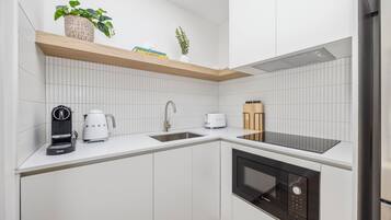 Una cocina moderna con armarios blancos, horno empotrado, cafetera y tostadora.