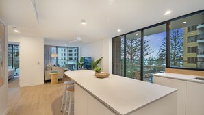 Een moderne keuken met een groot schiereiland, barstoelen en een uitzicht op de stad door grote ramen.