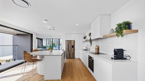 Een moderne keuken met een centraal eiland, witte kasten en een houten vloer.