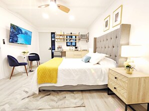 Een moderne hotelkamer met een bed, nachtkastje en een televisie aan de muur.
