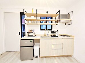 Cozinha compacta com geladeira embutida, pia e micro-ondas.