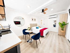 Ein modernes Hotelzimmer mit Bett, Schreibtisch, Stuhl, Esstisch und einem großen Spiegel.