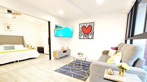 Une chambre d’hôtel moderne équipée d’un lit, d’un canapé, d’une télévision et d’un tableau représentant un cœur.