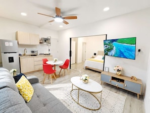 Un appartement moderne comprenant une cuisine, un coin repas, un salon et un téléviseur fixé au mur.
