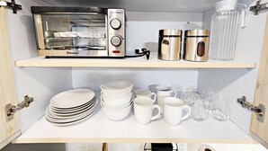 Une cuisine équipée d’un four à grille-pain encastré sur l’étagère supérieure, de tasses en acier inoxydable et d’un distributeur d’eau sur l’étagère inférieure.