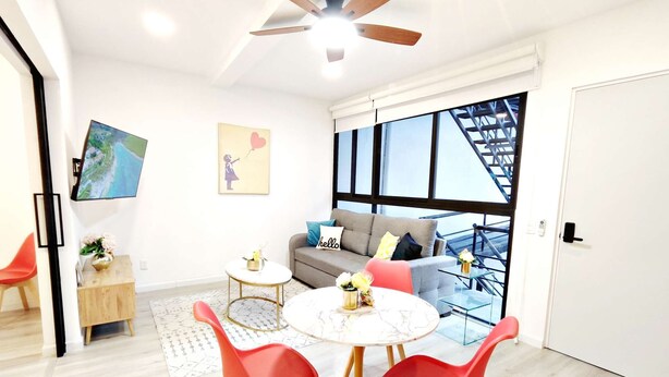 Un salon moderne avec un canapé, des fauteuils rouges, une table basse et un téléviseur fixé au mur.