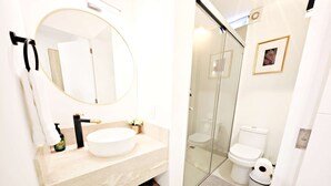 A modern bathroom with a round mirror, a beige sink, and a glass-enclosed shower. - Chic Polanco Loft: Prime Spot for Urban Explorers (Ciudad de México)