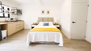 Un dormitorio con cama, mesitas de noche, ventilador de techo y una puerta.