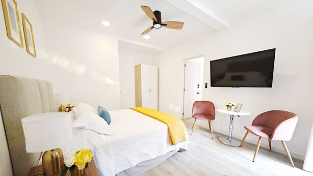 A modern hotel room with a bed, bedside table, lamp, and a ceiling fan. - Chic Polanco Loft: Prime Spot for Urban Explorers (Ciudad de México)