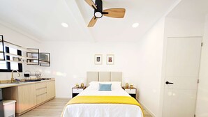 A modern bedroom with a bed, bedside tables, a ceiling fan, and a kitchen area with a sink and cabinets. - Chic Polanco Loft: Prime Spot for Urban Explorers (Ciudad de México)