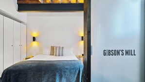 Ein Hotelzimmer mit einem Bett, zwei Wandlampen und einem Schild mit der Aufschrift "Gibson's Mill".